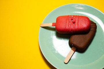 Chocolate cake pops in the form of ice cream on a stick. On a plate on a yellow background. Concept...