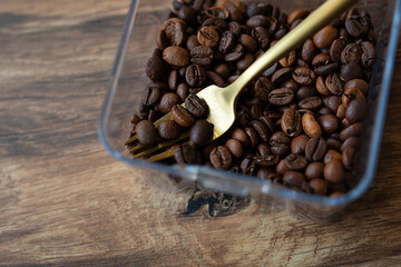 Roasted coffee bean in a plastic box along with a fork, close-up, top view. The concept of making coffee.