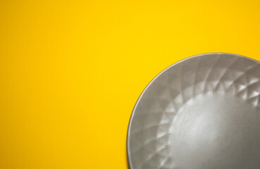 Gray plate for food on yellow background. Trending colors of 2021. Creative copy space
