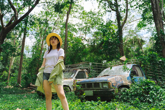 woman taking fashion photos with old classic car. A pretty woman in a straw hat stood in the woods