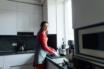Fototapeta na wymiar beautiful woman cooks in the kitchen to clean dishes