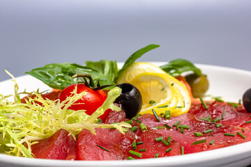 Tuna and salmon sashimi with lemon, olives and basil