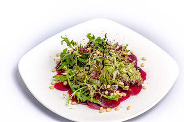Beetroot salad, frieze salad and pine nuts with balsamic vinegar is on a plate