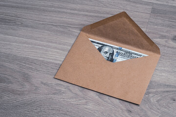 Dollar bills in a paper envelope on a wooden texture background. Bonus, reward, benefits concept