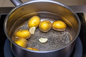 Potatoes in the peel are cooked in a saucepan with water and garlic