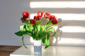 Red tulips in a vase on the shelf at home. Bouquet for Mothers day, home decoration