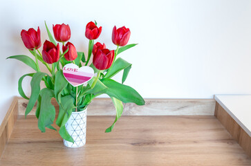 Red tulips in a vase on the shelf at home. Bouquet for Mothers day, home decoration
