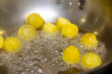 The cook is frying potato balls in a frying pan