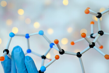 close-up of female scientist's hands holding model of molecular compounds on a blurred background,...