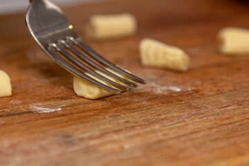 The cook correctly prepares the traditional Italian gnocchi dish with a fork.