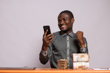 happy african man with a lot of money checks his phone and rejoices