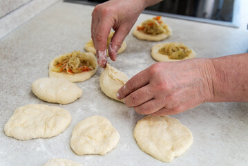 hands of a female cook put the stuffing in the pies.