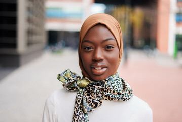 Black woman in hijab and scarf standing on street