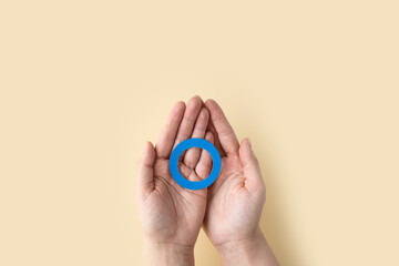 Fototapeta na wymiar World diabetes day inscription. Blue circle in woman hands on a beige background. 14 november.