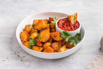 Traditional Spanish potato, patatas bravas with smoked paprika, spicy tomato sauce and parsley in a white bowl on gray stone background, top view. Delicious homemade food - 497120838