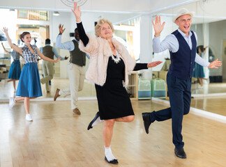Senior woman and younger man dancing swing in studio