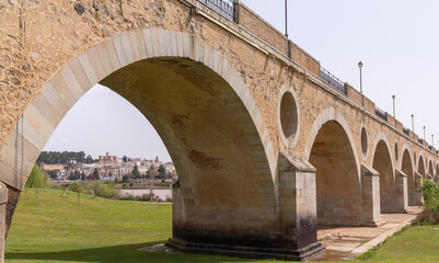 Fototapeta premium the historic 15-century Puente de Palmas Bridge with a view of the Old Town through one of the arches