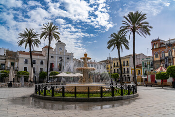 the Plaza de Espana Square in the city center of Merida with its fountain and palm trees - obrazy, fototapety, plakaty