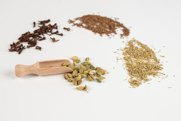 Cardamom in a wooden scoop. Cardamom in a wooden shovel on a white background.
