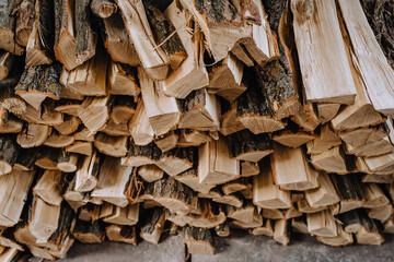 A lot of logs chopped with an ax, dry firewood of acacia, spruce stacked in a row close-up.