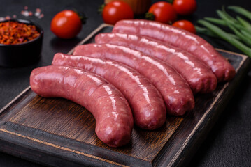 Raw sausages with ingredients on a cutting board on a stone background with copy space