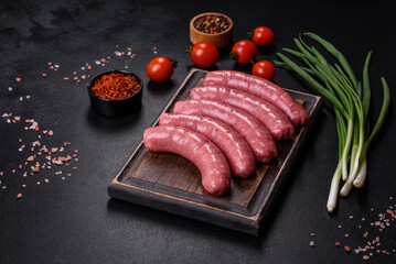 Raw sausages with ingredients on a cutting board on a stone background with copy space
