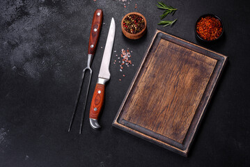 Brown rectangular wooden cutting board with salt and spices on a dark concrete background - Powered by Adobe