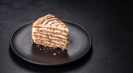 Esterhazy cake sliced on black plate close-up. Delicatessen sweet dessert with almond meringue dough and buttercream
