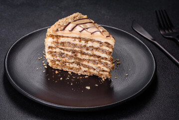 Esterhazy cake sliced on black plate close-up. Delicatessen sweet dessert with almond meringue dough and buttercream