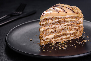 Esterhazy cake sliced on black plate close-up. Delicatessen sweet dessert with almond meringue dough and buttercream