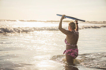 woman with Boogie board on the beach at the sunset