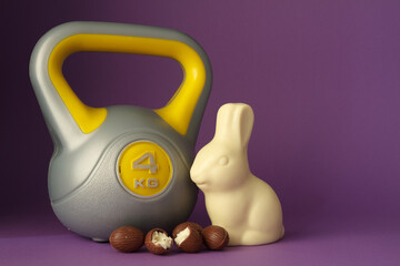 Kettlebell weight and chocolate Easter bunny. Healthy fitness lifestyle composition with copy space. Gym workout and training fit concept. Cheat day temptation vs sticking to diet.