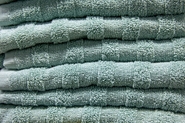 Textured green bath towels stacked close up.