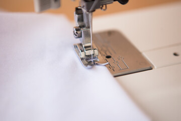 Sewing machine makes a seam on white fabric. Fragment of a sewing machine. Sewing process.