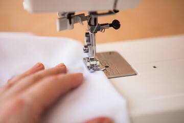 Woman sewing with sewing machine. Woman's hand and sewing machine at home.
