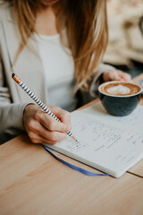 Close up of woman hands writing in a notebook with a cup of coffee, indoor study concept - 497126816