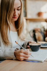 Close up of woman hands writing in a notebook with a cup of coffee, indoor study concept - 497126818