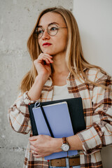 Portrait of young woman student in glasses with notebooks in hands - 497126836