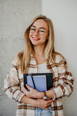 Portrait of happy young woman student in glasses with notebooks in hands - 497126838