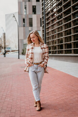 Young attractive happy woman walking in the city near the business buildings - 497126841