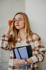 Portrait of young woman student in glasses with notebooks in hands - 497126842