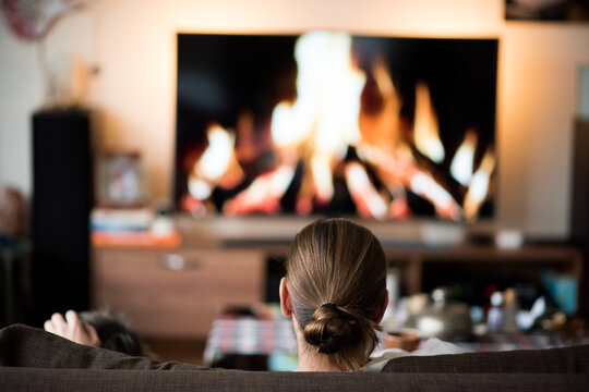 Rear view of man sitting on sofa in front of fireplace