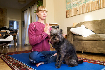 Woman meditating at home with dog