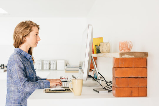 Young woman working from home on desktop pc