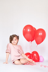 Fototapeta na wymiar Cute little girl holding a bunch of red heart-shaped balloons