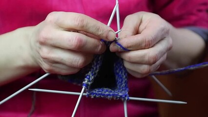 A housewife knits wool socks from blue threads on knitting needles.Close-up. Full HD slow motion video