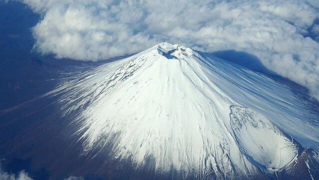 Top of Mt. Fuji.  Bird eyes view of big and high mountain Fuji of Japan. Mount Fuji Yama from sky above. Aerial view. With white snow on top and clouds around. Represent winter season of Japan.