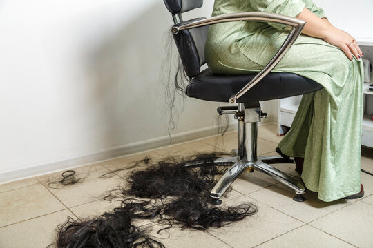 On the floor, long black hair cut and a woman in a barber's chair.