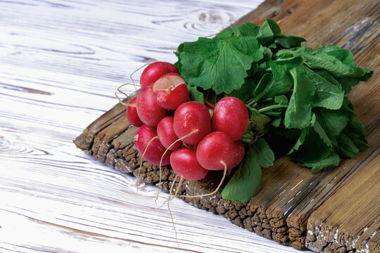 A bunch of fresh radishes with herbs on a wooden background.