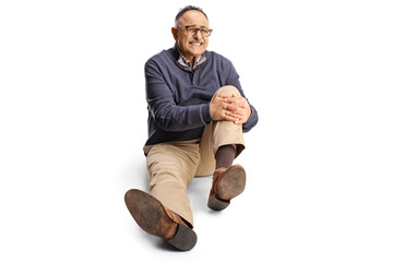 Mature man in holding his painful knee and sitting on the ground
